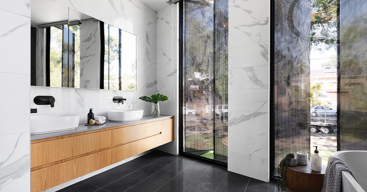 Big bathroom with white and black marble wall tiles and light timber cupboards