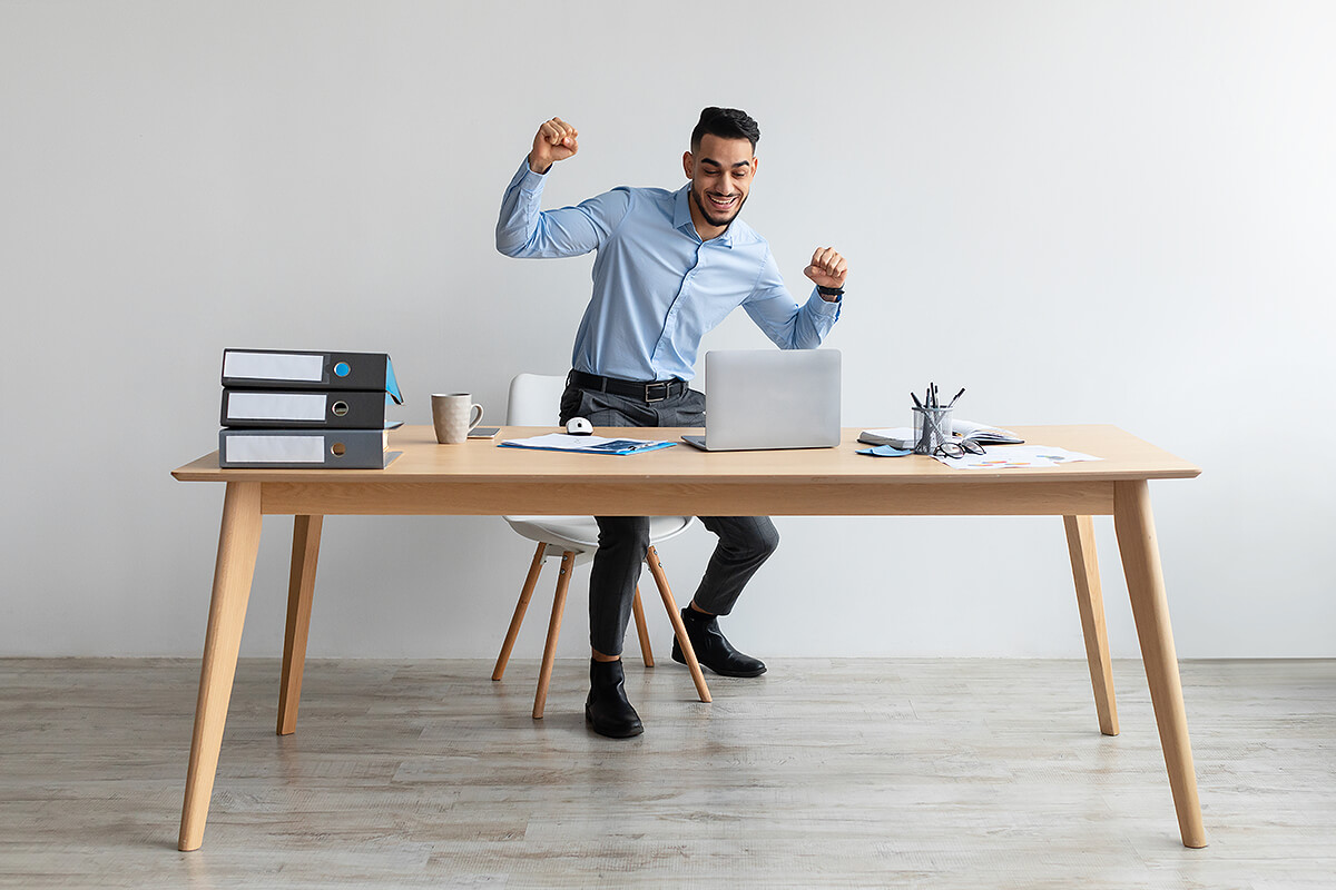 Excited man using laptop at office desk